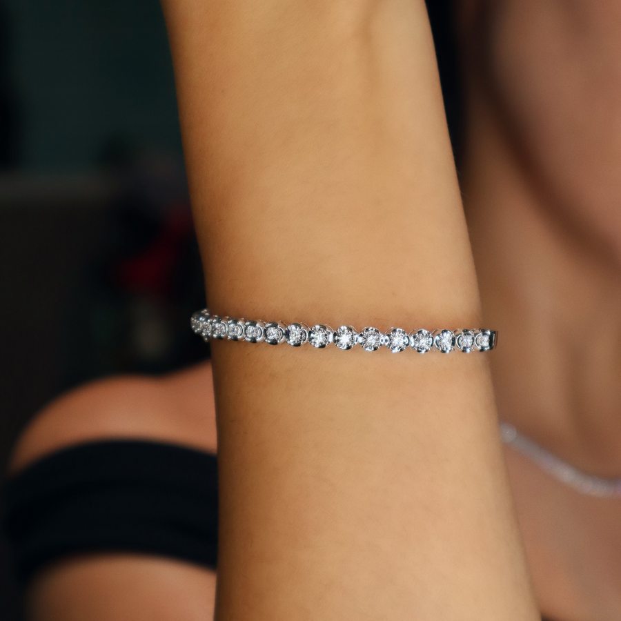 arm wearing a silver bracelet with small stones.